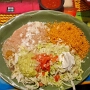20.03.2025 - Deluxe Burrito (A flour tortilla filled with shreddded beef, chile verde, chili colorado and beans. Topped with green chili sauce, cheesem guacamole, sour cream, lettuce, tomato and onion. Served with rice and refried beans topped with cheese). Das alles im Plaza Bonita Restaurant in Tusayan/AZ - 21,50 $ plus IceTea für 5 $