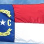 Flagge North Carolina<br />blau-weiss-rot, mit den Buchstaben N C, einem weissen Stern und 2 Daten, die auf der nächsten Seite beschrieben werden.<br /><br />Um 1650 zogen englische Siedler von Norden her in das Gebiet um den Albemarle Sound. Charles II. erlaubte 1663 die Gründung einer neuen Kolonie und legte dafür die Gemarkung fest. Er übergab das Land an acht Lord Proprietoren und benannte es zu Ehren seines Vaters Charles I. (lat. Carolus) Carolina. Im Jahr 1705 wurde Bath, die erste Stadt im heutigen North Carolina, gegründet. Carolina begann sich 1710 wegen Differenzen über Fragen der Regierungsform zu spalten, North Carolina und South Carolina entstanden. Letzteres wurde 1729 englische Kronkolonie, wodurch die Trennung auch offiziell vollzogen wurde.